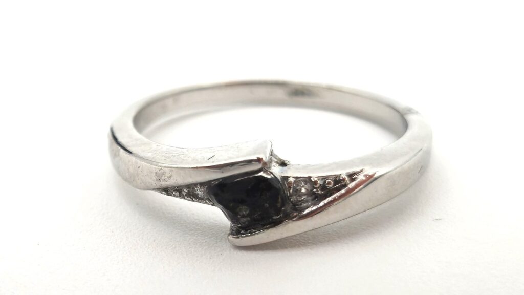 Silver ring set with a black meteorite fragment, on a white background